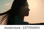 Portrait of girl, sun day, silhouette. Beautiful flowing female brown hair. Young woman looks at sky, prays, religious man. Girl hair flutters in wind, they believe in goodness, women dream of love.