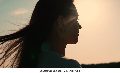 Portrait of girl, sun day, silhouette. Beautiful flowing female brown hair. Young woman looks at sky, prays, religious man. Girl hair flutters in wind, they believe in goodness, women dream of love. - Powered by Shutterstock