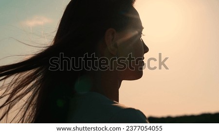 Portrait of girl, sun day, silhouette. Beautiful flowing female brown hair. Young woman looks at sky, prays, religious man. Girl hair flutters in wind, they believe in goodness, women dream of love.