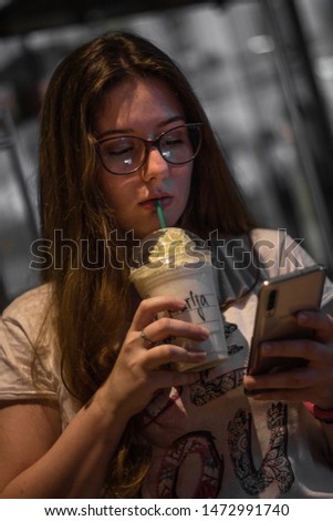 Portrait of girl with sunglasses holding phone and cup of white coffee