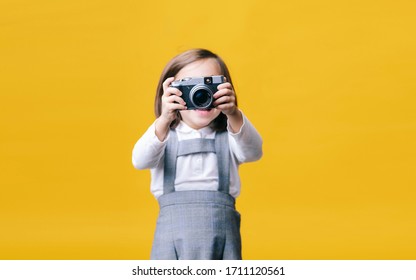 Portrait Of A Girl Using A Photo Camera On Yellow Background. Pic With Copy Space.