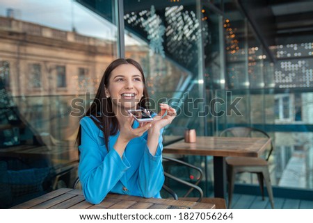 Portrait of a girl using the voice recognition on phone on a balcony