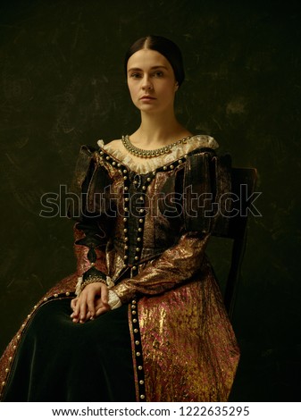 Portrait of a girl wearing a  antic 
 princess or countess dress over dark studio