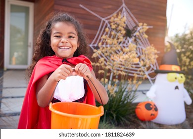 Portrait Of Girl Wearing Fancy Dress Outside House Collecting Candy For Trick Or Treat