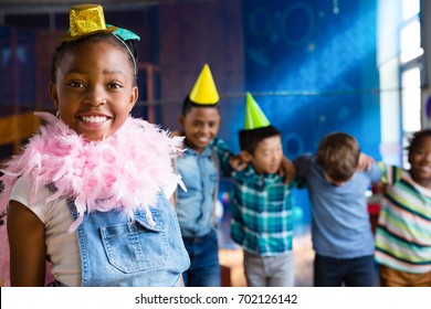 Portrait Of Girl Wearing Feather Boa With Friends In Background During Birthday Party