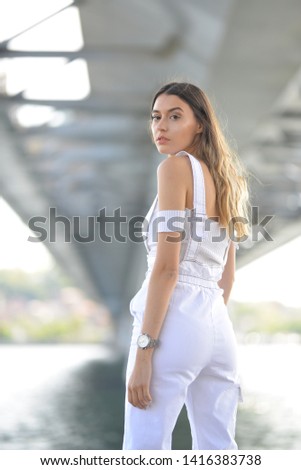 portrait of girl with white blouse and pants under the bridge