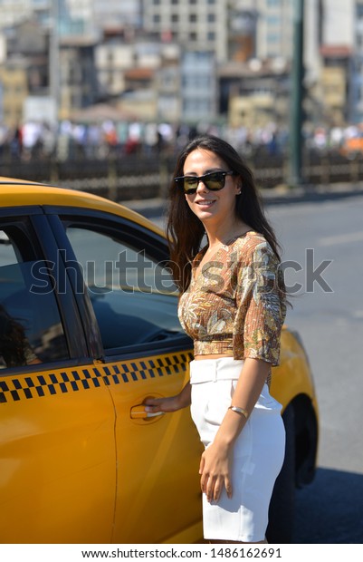 portrait of girl with yellow blouse and white shorts\
near the taxi in the\
city