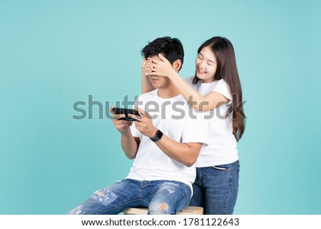 portrait of girlfriend close eye boyfriend for when using mobile phone for play game in green mint color background