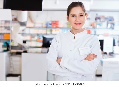 Portrait Of Glad Cheerful Positive Woman Pharmacist Who Is Standing On Her Work Place In Apothecary.