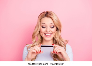 Portrait Of Glad Excited Girl With Modern Curly Hairdo Looking At Credit Card In Her Hands Going To Make Online Shopping Spending A Lot Of Money Isolated On Pink Background