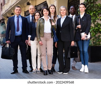 Portrait of glad positive successful business people of different ages and nationalities standing together on city street