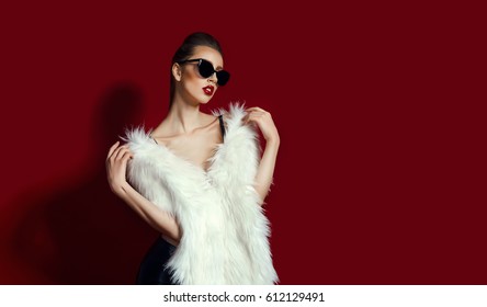 Portrait Of Glam Girl In White Fur On Red Background. Fashion Photo