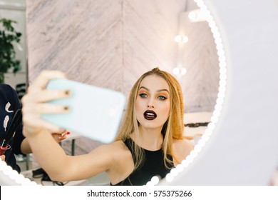 Portrait Glamour Fashionable Young Woman With Long Blonde Hair Making Selfie In Mirror In Hairdresser Saloon. Elegant Look, Red Lips, Making Hairstyle, Preparing To Celebration