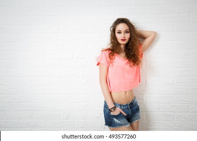 Portrait of Glamour Hipster Girl on White Brick Wall Background. Trendy Casual Fashion Makeup. Toned Photo with Copy Space.