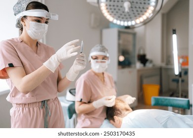 Portrait of gloved female nurse prepares filled syringe by tapping syringe and giving to doctor for injection. Anesthesiologist in mask removing air bubbles from syringe by tapping it. - Powered by Shutterstock