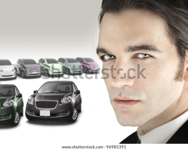 Portrait of a good\
looking car salesman in close up view against background of luxury\
bright car dealership