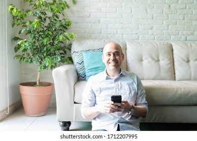 Portrait of a good looking Caucasian bald man using a smartphone at home and smiling - Shutterstock ID 1712207995