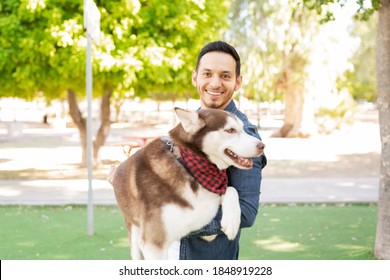 Portrait Of A Good Looking Hispanic Guy Carrying His Big Beautiful Dog Pet In The Park