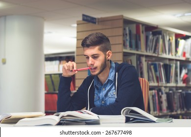 Portrait Of Good Looking Male Student Reading And Doing Research In The Library. Lifestyle Image Of University Student Studying For Exam In England With Vintage Blue Filter. Knowledge Is Power Concept