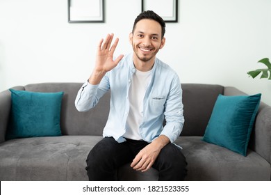 Portrait Of A Good Looking Man Waving And Saying Hello To The Camera In A Video Call From Home