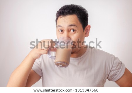 Portrait of good looking young Asian man drinking iced coffee,  milk tea or cold chocolate