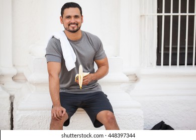 Portrait Of A Good Looking Young Athlete Eating A Banana To Recover From His Workout Outdoors In The City