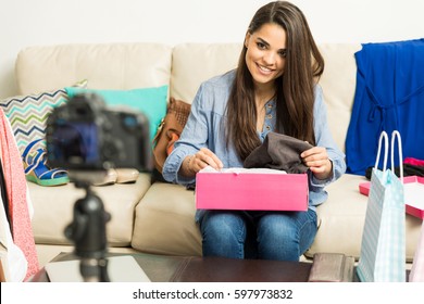 Portrait Of A Good Looking Young Brunette Opening A Box Of Shoes While Recording A Video Blog