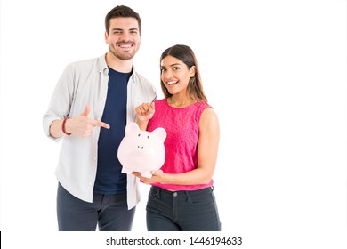 Portrait Of A Good Looking Young Couple Holding Their Savings In A Piggy Bank Against Plain Background