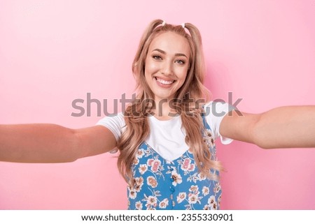 Portrait of good mood pretty girl with ponytails wear white t-shirt making selfie on frontal camera isolated on pink color background
