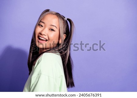 Portrait of good mood pretty girl with ponytails wear oversize pullover stand near logo empty space isolated on violet color background