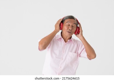 Portrait Of A Good-looking Full Of Energy And Active Senior Older Asian Man Holding And Wearing Red Headphone And Listening To Music With Joyfully And Happy Face And Deep Emotion On White Background