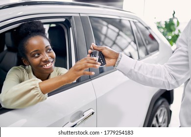 Portrait Of Good-looking Lady Getting Keys By Car, Woman Make Purchase In Cars Showroom. She Sits Inside Of Beautiful Car And Look At Sales Agent