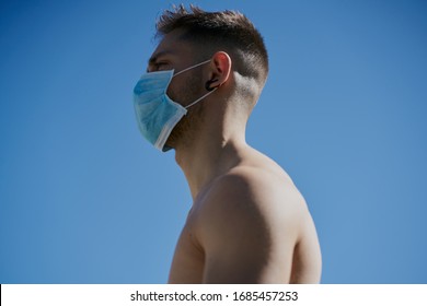 Portrait Of A Gorgeous Guy Wearing A Mask To Avoid Contagion While Walking Down The Street. Coronavirus Concept