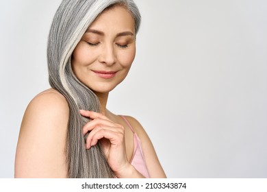 Portrait of gorgeous happy middle aged mature cheerful asian woman, senior older 50s lady pampering her hair eyes closed isolated on white. Ads of lifting anti wrinkle skin hair care spa. Copy space.