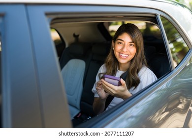 Portrait Of A Gorgeous Hispanic Woman Taking A Rideshare Car And Using The Mobile App On Her Phone 