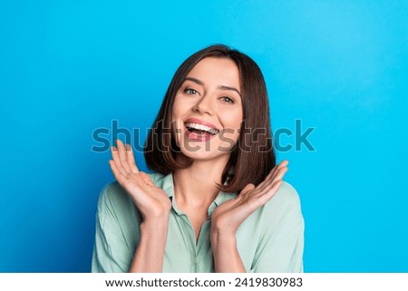 Portrait of gorgeous lovely girl with stylish hair wear teal shirt palms demonstrate white toothy smile isolated on blue color background