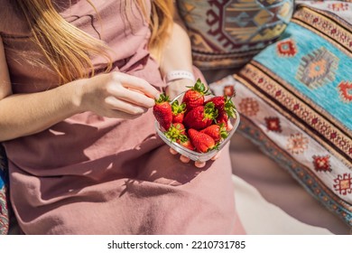 Portrait of gorgeous woman wearing beautiful dress sitting in a patio and eating strawberry