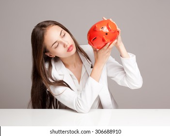 Portrait of a gorgeous young brunette woman holding piggy bank. Stock Photo