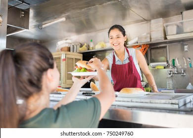 Portrait of a gorgeous young woman working in a food truck and selling hamburgers with a smile - Powered by Shutterstock