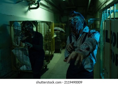 Portrait Of Gory Zombie Reaching Out To Camera While Standing In Dark Industrial Hallway, FX Makeup, Copy Space