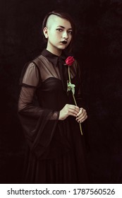 Portrait Of A Goth Teenager Wearing A Black Dress With Shaved Hair On One Side Holding A Red Rose. Great For Book Cover