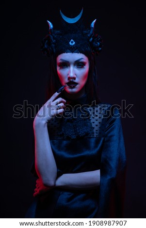 Portrait of gothic woman in balck clothes posing in studio on dark background