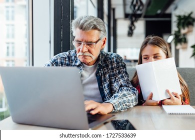 Portrait of grandfather and granddaughter doing homework with laptop. - Powered by Shutterstock