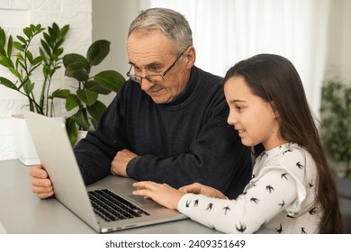 Portrait of grandfather and granddaughter doing homework with laptop. - Powered by Shutterstock