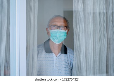 Portrait Of Grandfather Looking Through The Window While Wearing Facial Mask And Doing Self Isolation