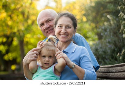 Portrait Of Grandma And  Grandpa With Little Grandaughter Outdoor