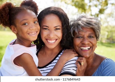 Portrait Of Grandmother With Adult Daughter And Granddaughter Relaxing In Park