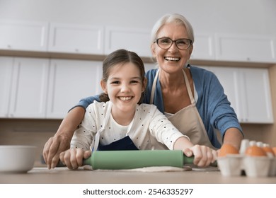 Portrait of grandmother and granddaughter flattening dough together, preparing holiday pie, make homemade baked pastry. Family bonding, teaching process, shared activities across generations, cookery - Powered by Shutterstock