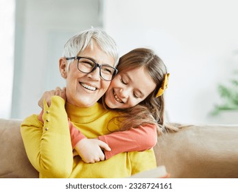 Portrait of grandmother and granddaughter having fun together reading a book at home - Powered by Shutterstock