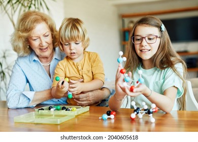 Portrait of grandmother and grandson and granddaughter having fun with a chemistry molecular atom model tool learning biology and chemistry class together at home - Powered by Shutterstock